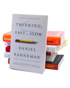 Stack of books with Thinking fast and slow book by Daniel Kahneman in front